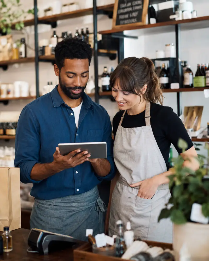 Two shop staff reviewing a tablet together at the counter